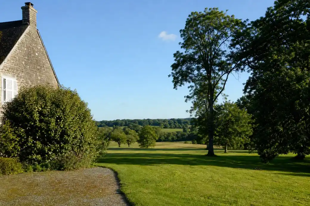 Grande propriété rurale à Lonrai avec vaste pelouse tondue ouverte sur les prés et les bois, fond de parcelle débroussaillé et grands arbres élagués, ambiance de bocage normand.